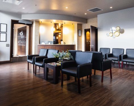 Modern waiting room with black chairs and reception.