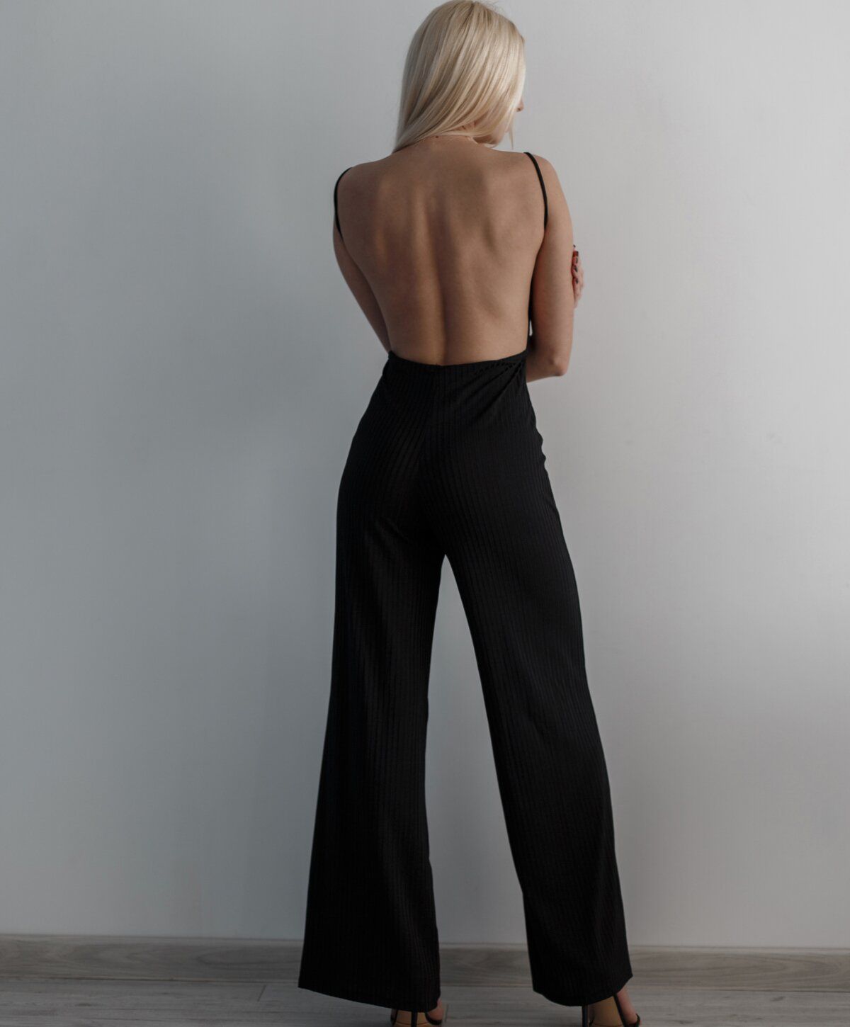 Back view of a model in black jumpsuit.
