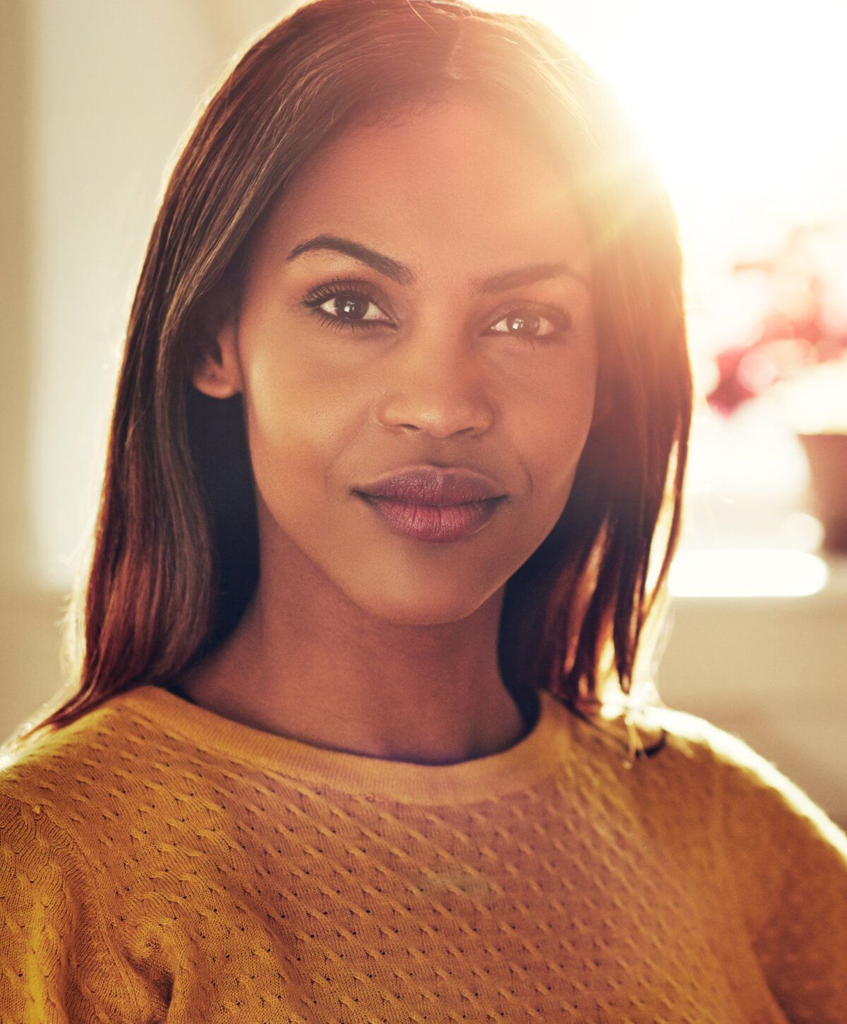 Woman in yellow sweater with sunlight background.