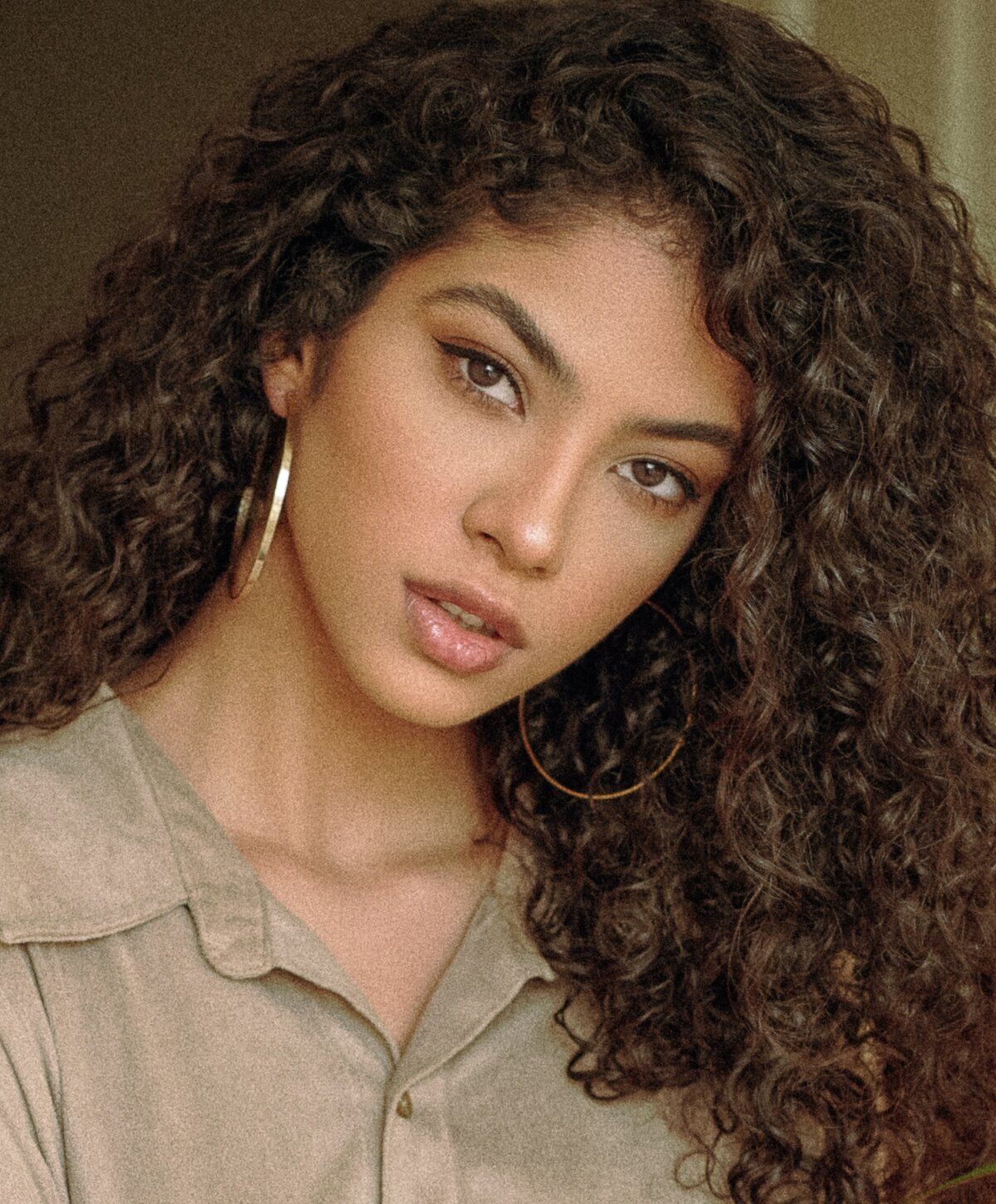 Young woman with curly hair and hoop earrings.