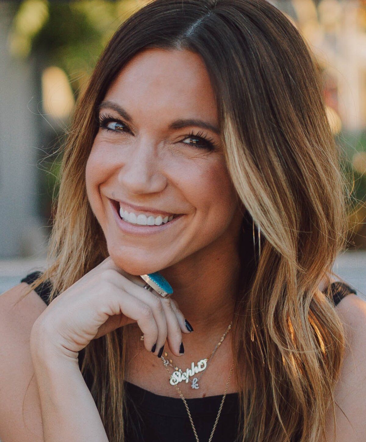 Smiling woman with long hair and jewelry.