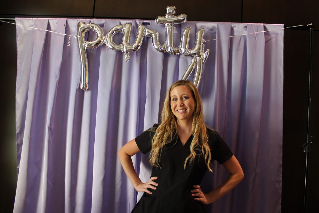 MidAmerica staff member posing in front of party backdrop