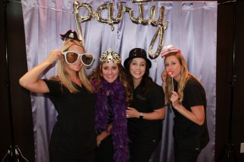 MidAmerica staff posing with various props in front of a party backdrop